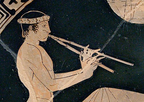 Ancient Greek red-figure vase painting of a reclining banqueter playing the double aulos, one pipe held in each hand.
